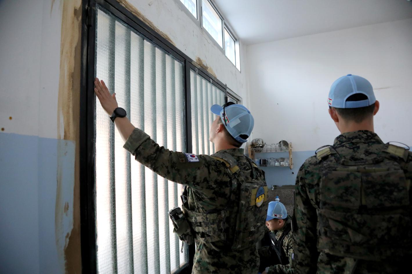 A peacekeeper installing a window in a school